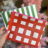 Two fabric pouches with green and white striped and red and white checkered patterns held by a hand.