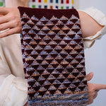 Person holding a patterned knitted scarf with a colorful background