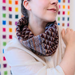 Person wearing a patterned scarf against a colorful geometric background