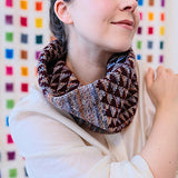 Person wearing a patterned scarf against a colorful geometric background