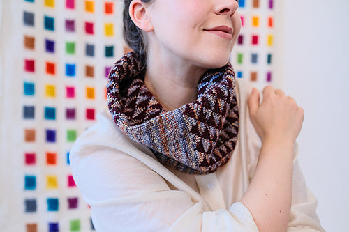 Person wearing a patterned scarf against a colorful geometric background